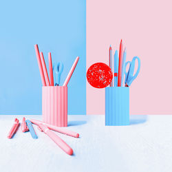 Blue and pink plastic pencil-boxes with pencils, pens, scissors and red candy. space for copy.