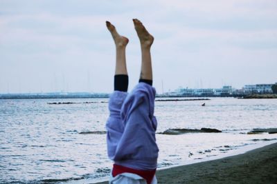 Rear view of man standing at beach against sky