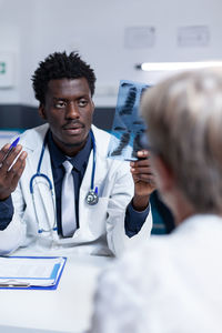 Male doctor with x-ray image talking with patient at clinic