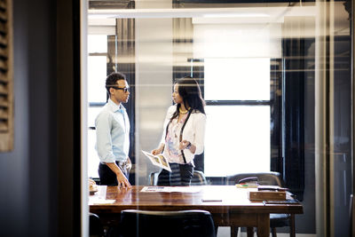 Businesswoman talking to colleagues while standing in office