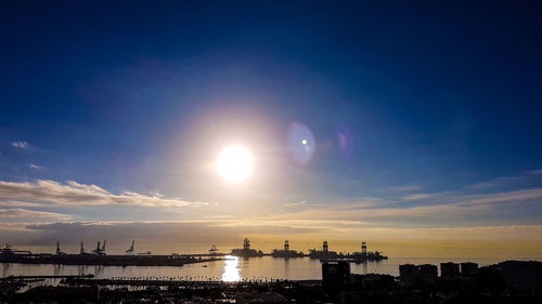 Buildings by sea against sky during sunset