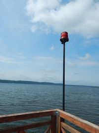 Street light by sea against sky