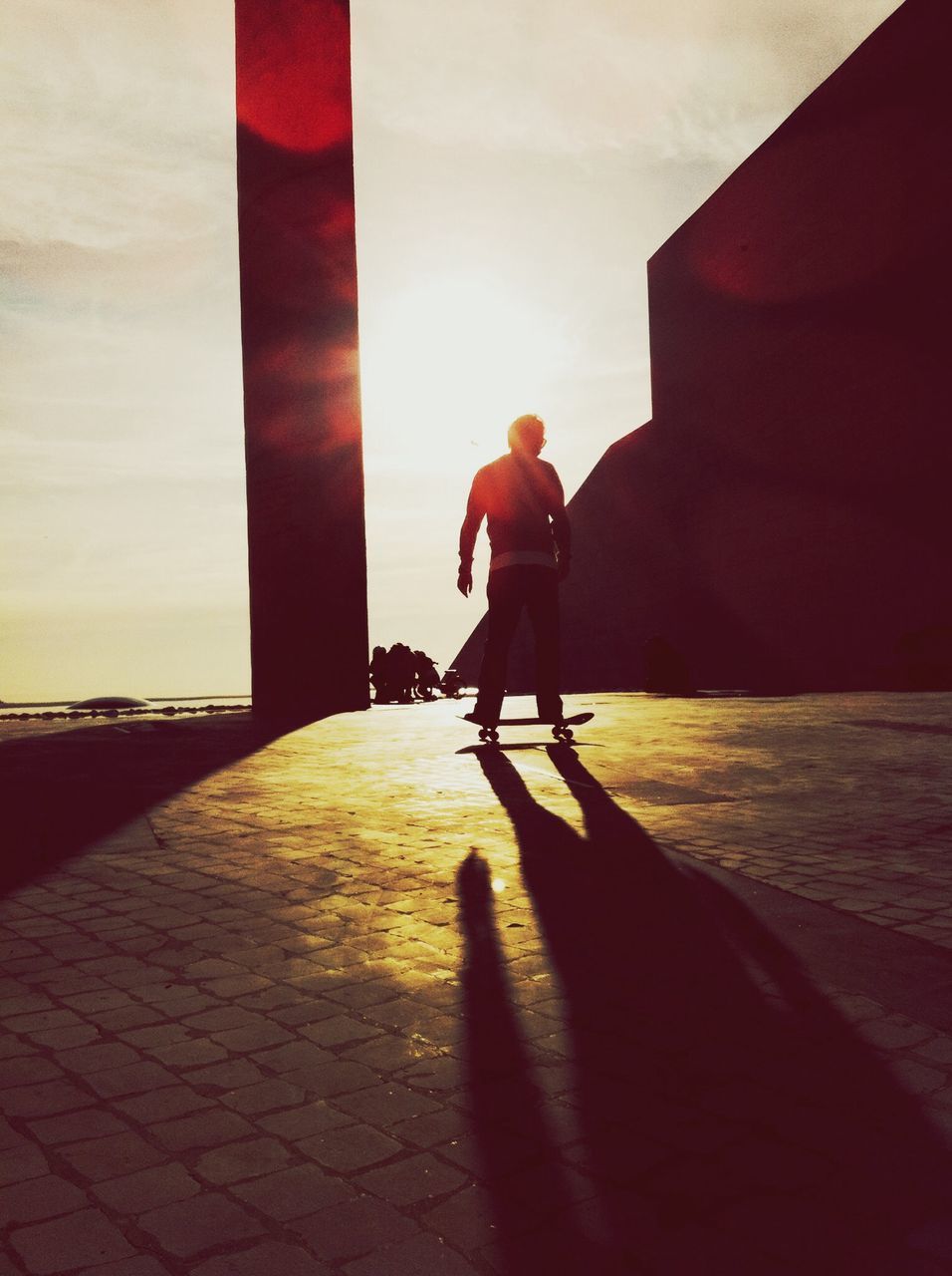 full length, lifestyles, rear view, sunset, leisure activity, men, silhouette, built structure, walking, sunlight, architecture, person, building exterior, sky, standing, shadow, casual clothing