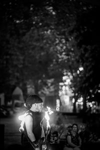 People standing by illuminated tree at night