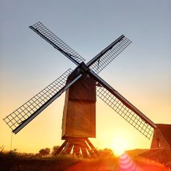 Low angle view of traditional windmill on field against sky