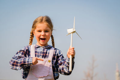 Portrait of young woman holding umbrella against clear sky