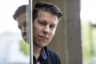 Close-up portrait of mature man standing against wall