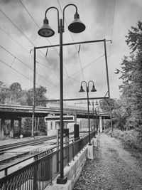 Street lights by railroad tracks against sky