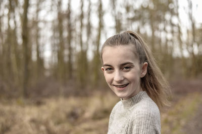 Close-up portrait of smiling teenage girl in forest