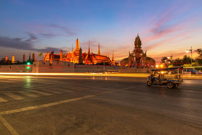 Illuminated city buildings against sky during sunset