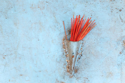 Close-up of incense against blue wall