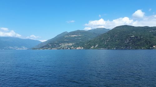 Scenic view of sea by mountains against sky