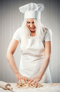 Young woman screaming while kneading flour in kitchen