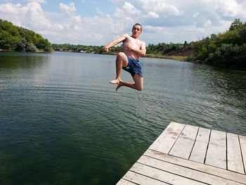 Man diving in lake against sky