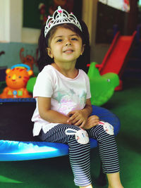 Portrait of cute girl wearing crown sitting on trampoline