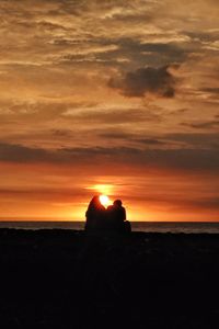 Silhouette rock in sea against sky during sunset