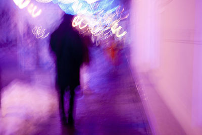 Rear view of people walking in illuminated city