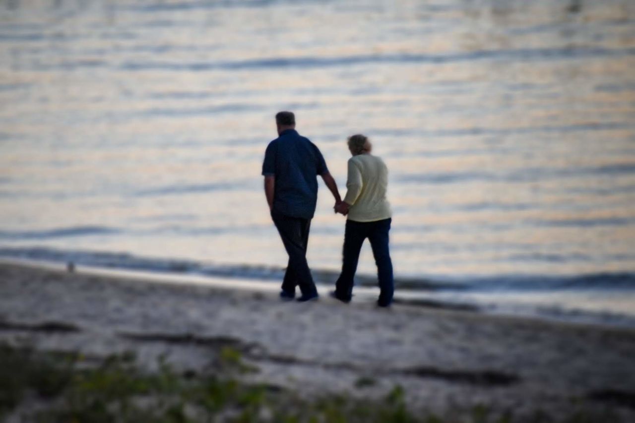 REAR VIEW OF MEN WALKING ON SHORE