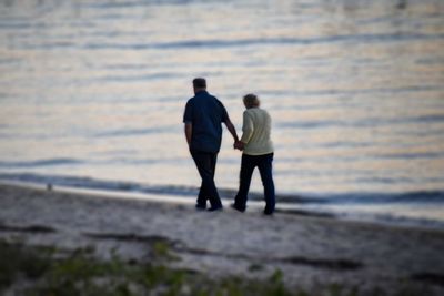 Rear view of men walking on beach