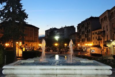 Canal in city against clear blue sky at night