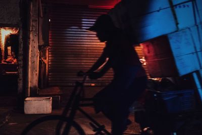 Side view of woman walking on building at night