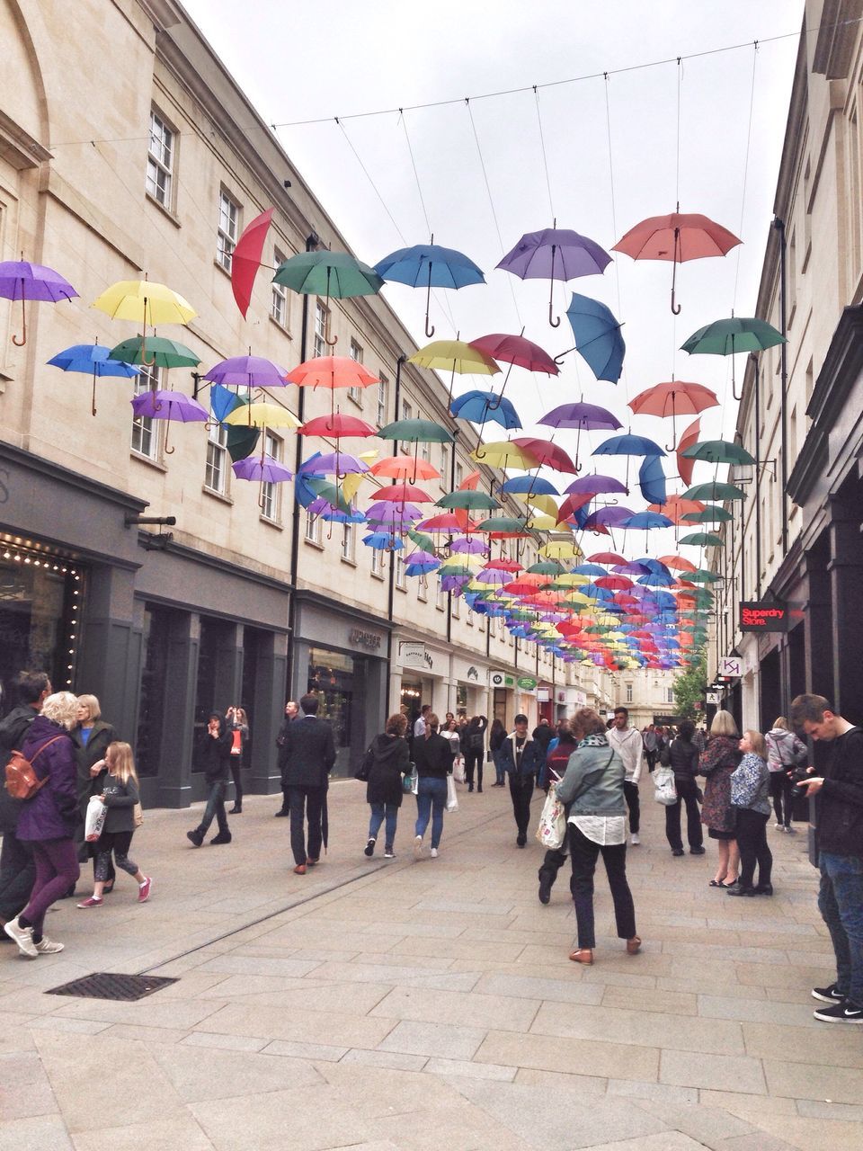 large group of people, architecture, built structure, person, men, building exterior, lifestyles, crowd, city life, mixed age range, walking, city, leisure activity, street, flag, multi colored, text, market, day