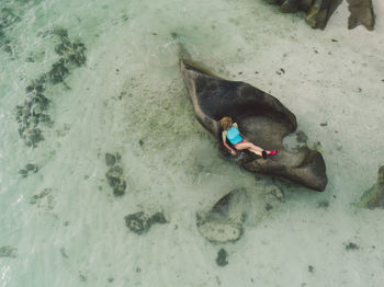 High angle view of woman lying on rock at beach