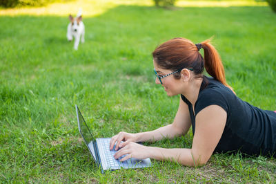 Side view of young woman using mobile phone in field