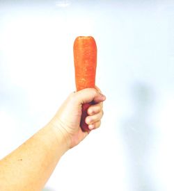 Close-up of hand holding ice cream against sky