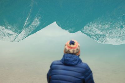 Rear view of man on beach against sky during winter