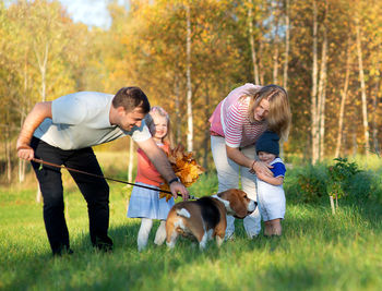 Happy family with dog on grass during autumn