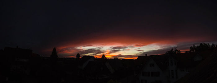 Silhouette houses against sky during sunset