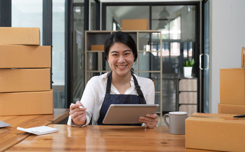 Portrait of young woman using mobile phone while sitting in cafe