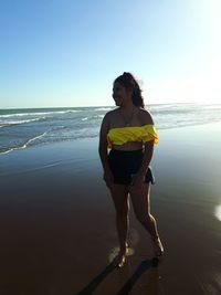 Young woman standing on beach against clear sky