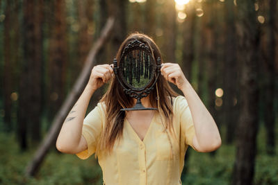 Woman with mirror instead of face on the forest background. mindfulness, mind and soul, mental