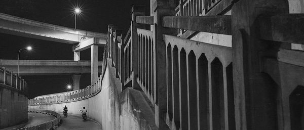 Low angle view of steps by road against overpass at night