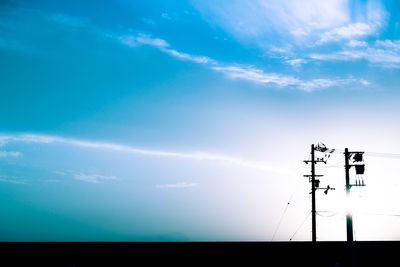 Low angle view of electricity pylon against blue sky