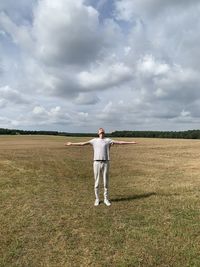 Rear view of man standing on field against sky