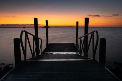 Pier over sea against sky during sunset