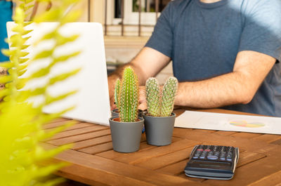 Midsection of man holding coffee while sitting on table