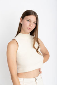 Portrait of young woman standing against white background