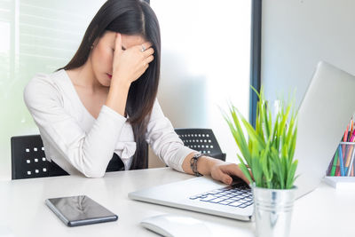 Midsection of woman using mobile phone while sitting on table