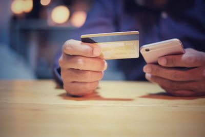 Close-up of man using mobile phone on table