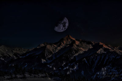 Scenic view of snowcapped mountains against sky at night