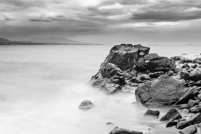 Rock formation on beach against sky