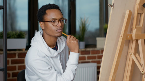 Young man with pencil sitting in studio