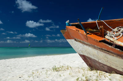 Abandoned fishing boat in palm beach, with a sailboat on the horizon. aruba