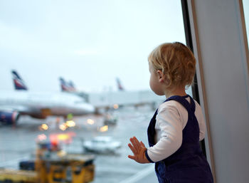 Boy looking through window at airport