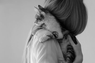 Side view of mid adult woman with kitten standing against white background