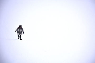 Rear view of man walking on snow covered landscape